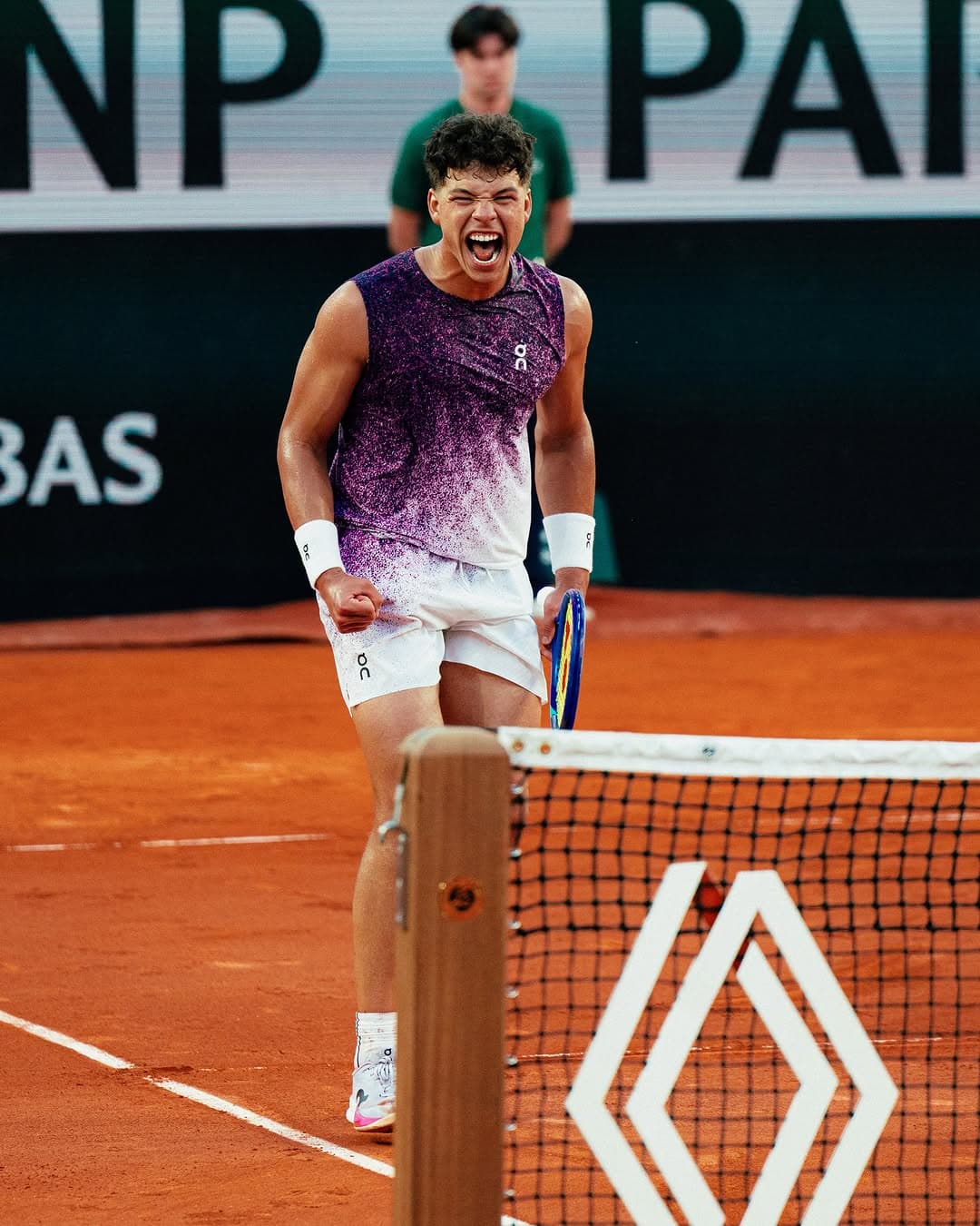 Ben celebrates with a fist pump on red clay at Roland Garros, wearing purple On gear and white wristbands.