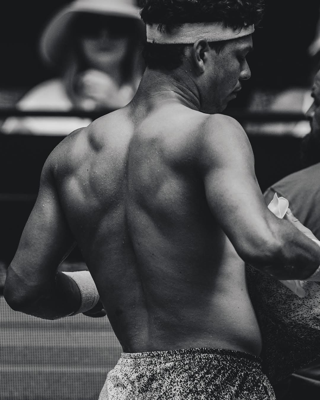 Ben Shelton shirtless during training, sweat-covered, wearing a headband and towel.